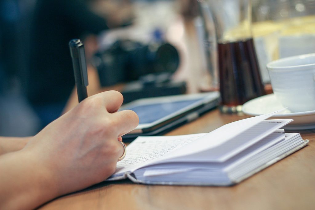 Une personne prend des notes dans un carnet à son bureau de travail