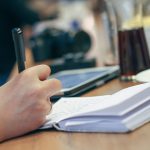 Une personne prend des notes dans un carnet à son bureau de travail