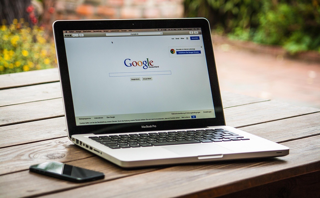 Ordinateur portable posé sur une table en bois affichant le moteur de recherche Google