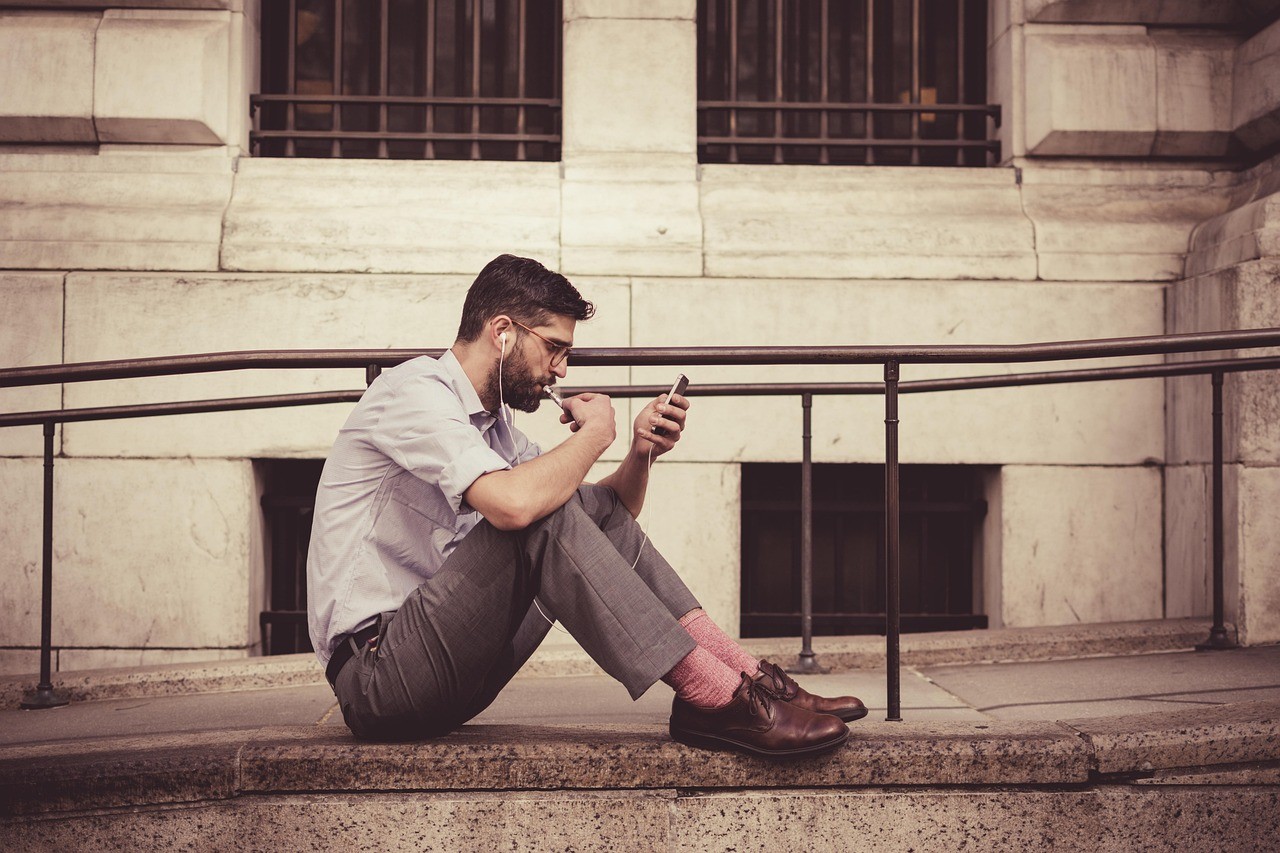 Personne assise sur des marches consultant son smartphone à l'extérieur