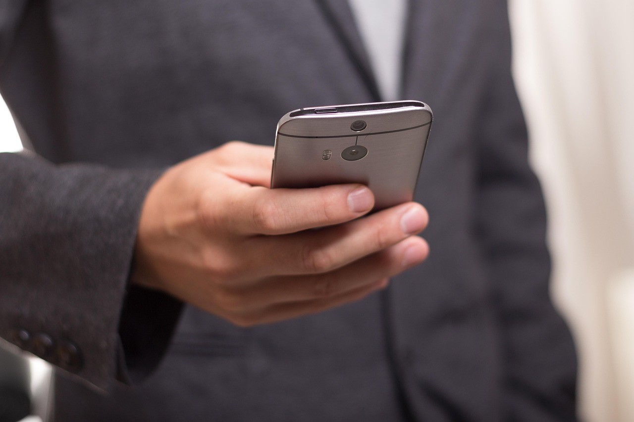 Personne qui lit l'écran de son smartphone tenu à la main