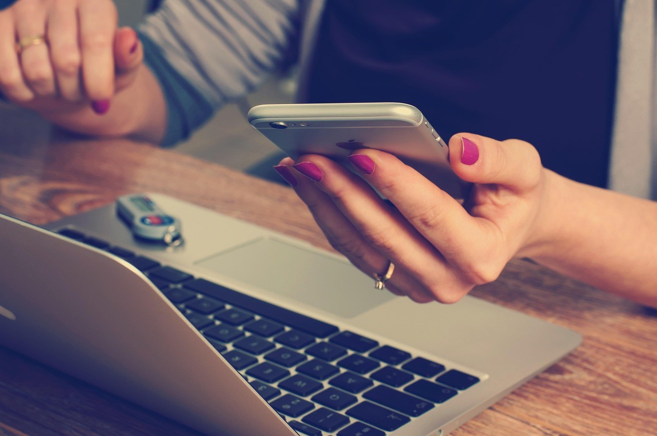 Deux personnes consultant une réponse sur un smartphone devant un ordinateur portable