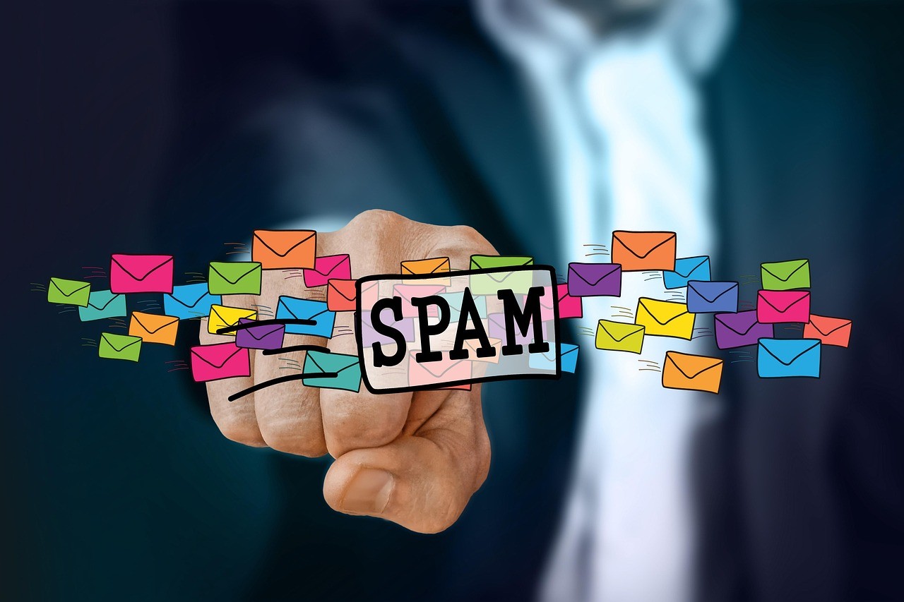 Une main tenant un panneau où est écrit SPAM, entourée d'icônes d'enveloppes de courrier