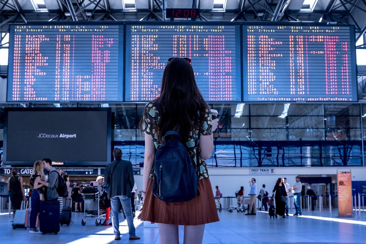 Voyageuse consultant un tableau des départs de vols dans un aéroport