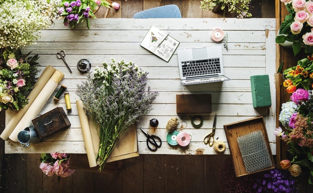 Propriétaire d'une petite boutique (fleuriste) qui consulte son site en ligne depuis un ordinateur portable, sur son établi