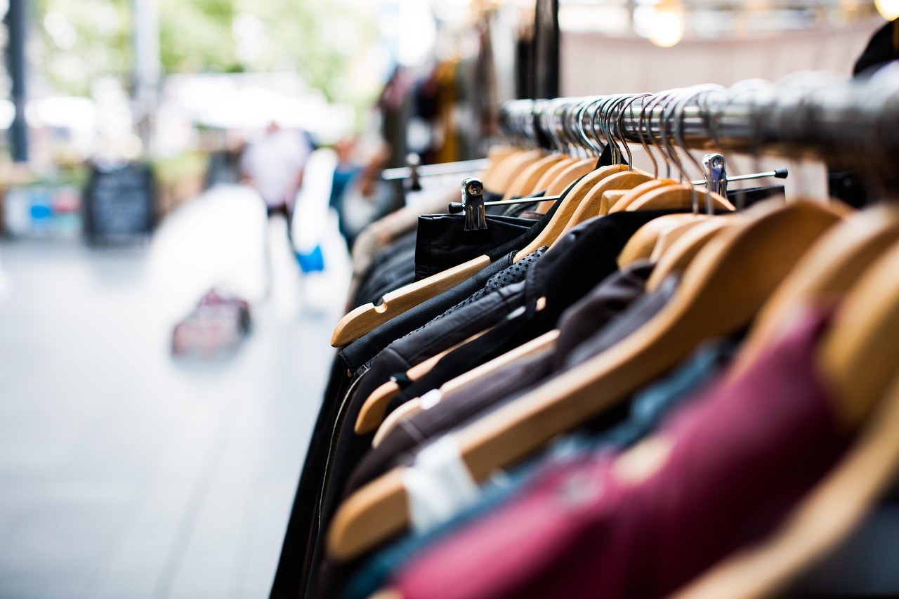 Portant de vêtements dans une petite boutique, exemple de commerce pouvant baliser ses fiches produits