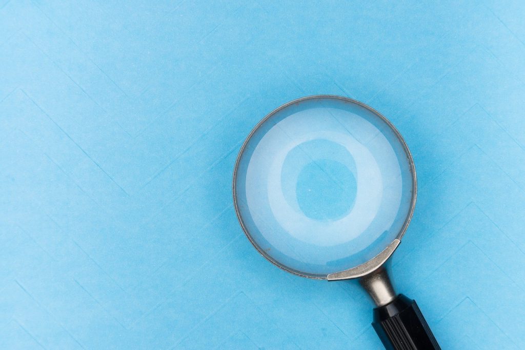 Loupe posée sur un fond bleu, symbole de recherche et de vérification