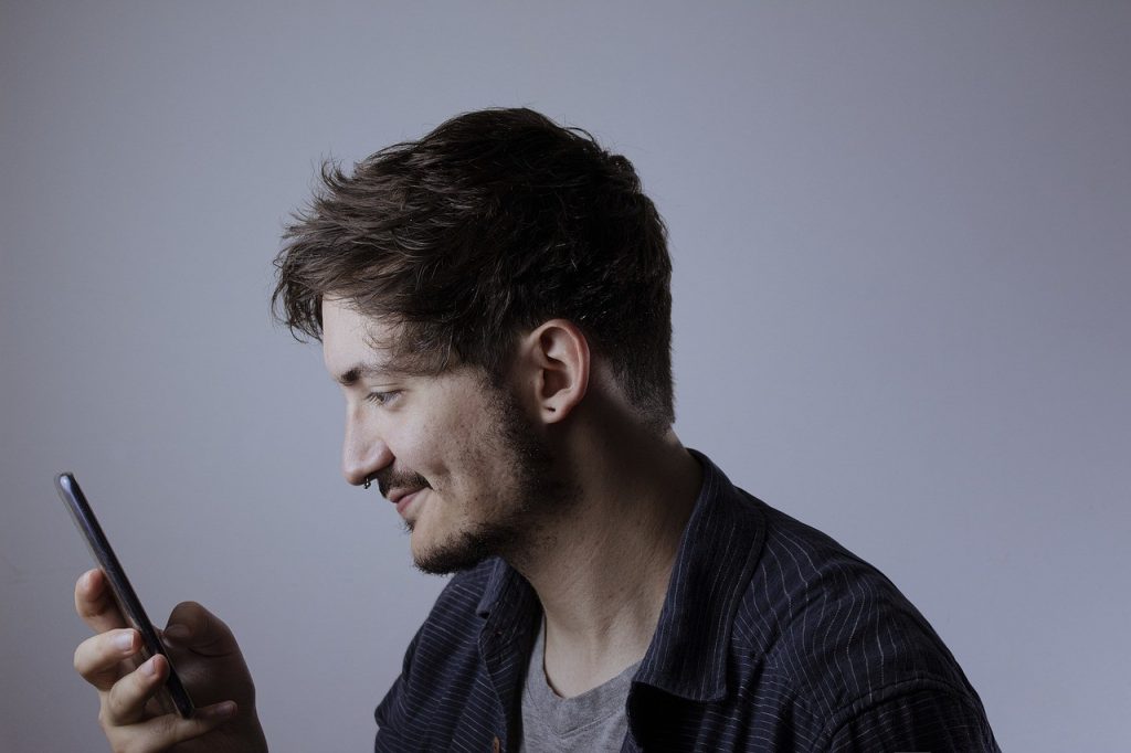 Un homme souriant consulte une réponse sur son smartphone