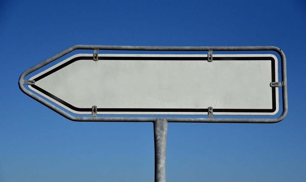 Panneau directionnel vierge en forme de flèche, sur fond de ciel bleu