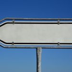 Panneau directionnel vierge en forme de flèche, sur fond de ciel bleu