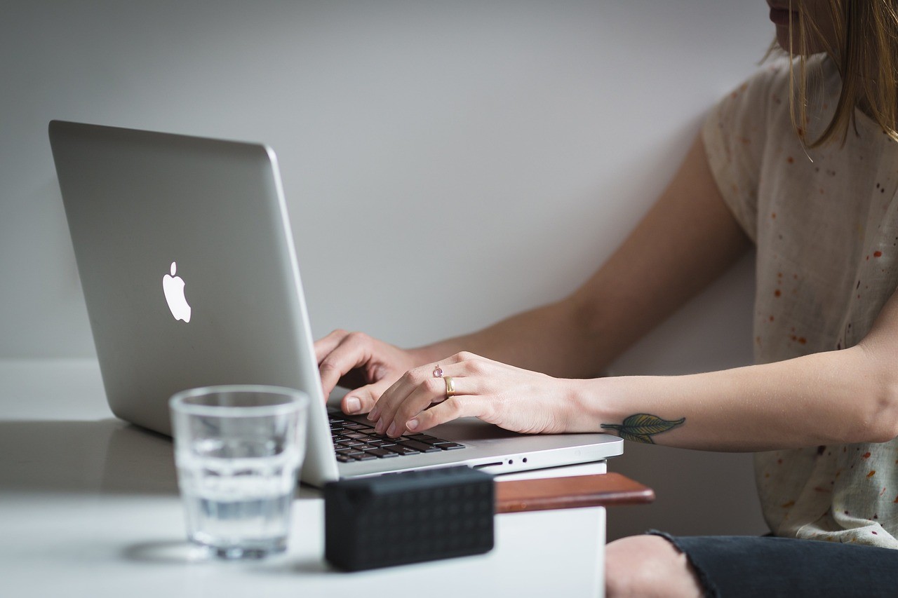 Mains tapant sur un clavier d'ordinateur portable pour rédiger du contenu