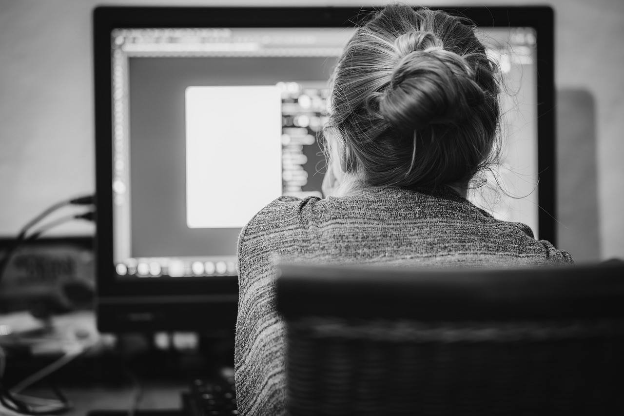 Personne de dos travaillant sur un ordinateur dans un bureau à domicile