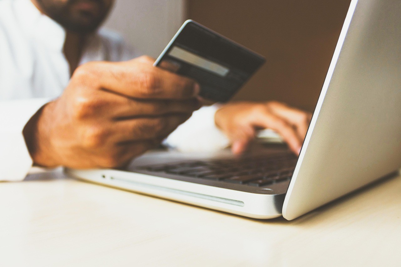 Paiement par carte bancaire devant un ordinateur portable, illustrant un lien payé