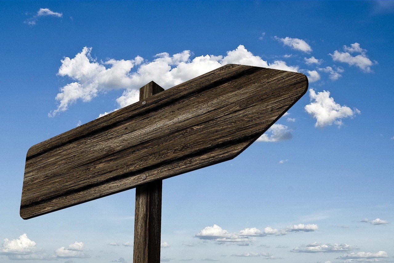 Panneau de signalisation en bois pointant une seule direction sous un ciel bleu