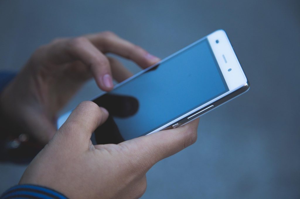 Gros plan de deux mains tenant un smartphone pour naviguer sur un site web